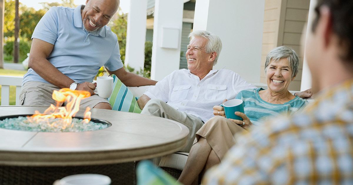 Happy family and friends having coffee around fire pit table